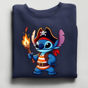 K&ouml;nnte beinhalten: Marineblaues Sweatshirt mit einem Cartoon-Piraten. Die blaue Figur tr&auml;gt einen Piratenhut mit Totenkopf, ein rotes Halstuch und ein orange-wei&szlig; gestreiftes Hemd. Die Figur h&auml;lt eine brennende Fackel. Das Sweatshirt ist ein l&auml;ssiges Kleidungsst&uuml;ck.