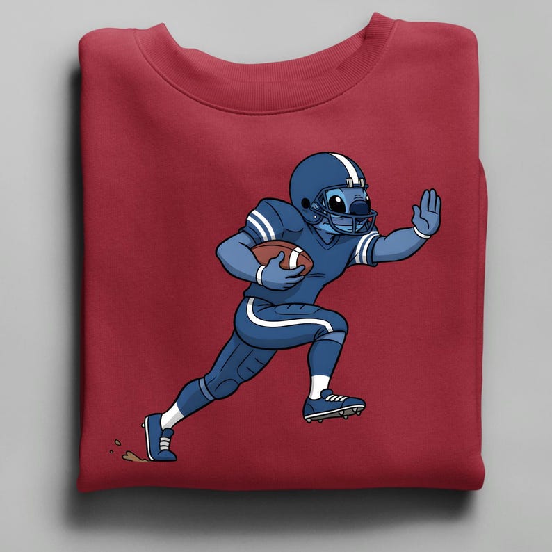 May include: A maroon sweatshirt with a cartoon character in a blue American football uniform, including a helmet and pads, running with a football. The character is light blue with white stripes.