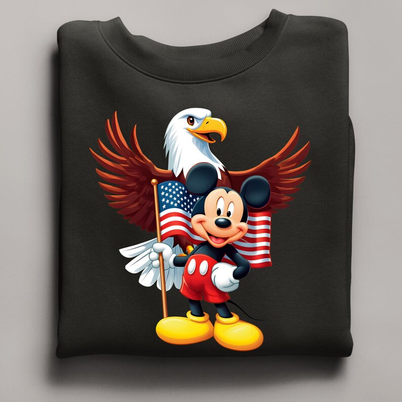 May include: Black sweatshirt featuring a graphic of Mickey Mouse holding an American flag, with a bald eagle behind him. The eagle has brown and white feathers, and the flag has red and white stripes and blue stars. Mickey is wearing red shorts and yellow shoes.