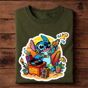 May include: Olive green t-shirt featuring a colorful graphic of Stitch from Lilo & Stitch. Stitch is holding a water gun, wearing headphones and a lei, with the text "Aloha Party Mode".