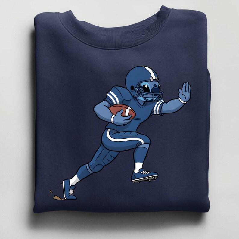 May include: Navy blue sweatshirt with a cartoon character in a blue American football uniform. The character, blue with white stripes, is running with a football. The sweatshirt is folded. The character is wearing a helmet and pads.