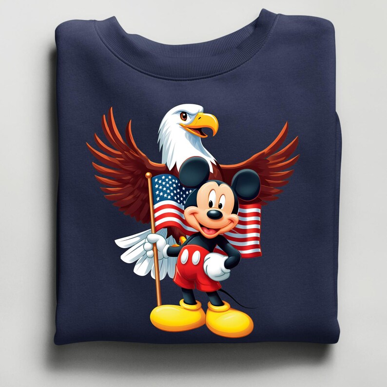 May include: Navy blue sweatshirt featuring a cartoon Mickey Mouse holding an American flag, with a bald eagle behind him. The eagle has brown wings and a white head. Mickey Mouse is wearing red shorts and yellow shoes.