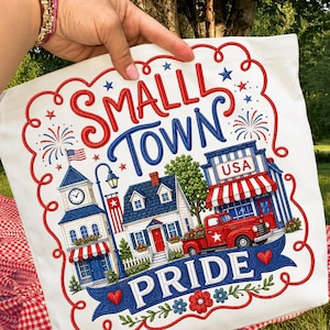 May include: White tote bag with a patriotic design featuring the words "SMALL TOWN PRIDE." The design includes a clock tower, houses, a red truck, and fireworks, all in red, white, and blue.