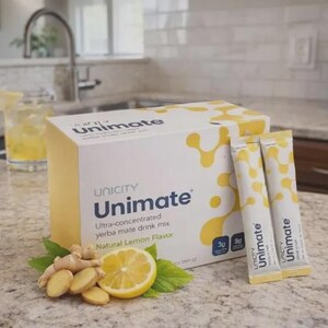 Pu&ograve; includere: Una scatola e bustine di Unicity Unimate yerba mate drink mix al gusto limone naturale. La scatola &egrave; bianca con dettagli gialli, le bustine sono gialle e bianche. Zenzero a fette e met&agrave; limone sono accanto.