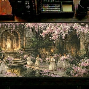 May include: A rectangular desk mat featuring a printed illustration of children in white dresses holding flowers near a stone shrine and a pond. The scene includes stone arches, hanging pink blossoms, and a statue. The mat is on a dark wooden desk.