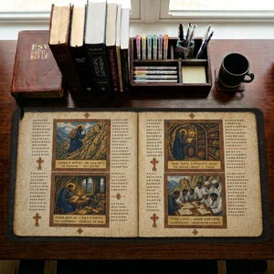 May include: An open book with illustrations and text, featuring a dark brown leather cover. The book is on a wooden desk with other books, pens, and a coffee mug. The illustrations depict religious scenes with figures in robes.