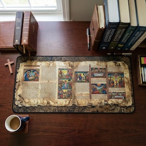 May include: A desk setup featuring a large, rectangular mousepad with an aged, illustrated biblical scene. The pad is surrounded by books, a coffee cup, and a wooden cross. The illustrations are in vibrant colors.