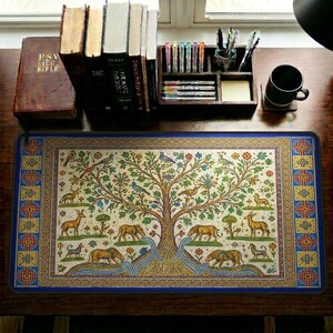 May include: A rectangular desk mat with a detailed mosaic design featuring a tree, animals, and birds. The mat has a blue border with geometric patterns. The tree has colorful leaves and is surrounded by deer, bears, and other creatures.