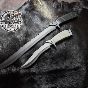 May include: Two knives with black blades and handles, one long with a serrated edge and the other shorter with a curved blade. The handles are black and tan. The knives are displayed on a dark, textured surface. The logo "H.A. BLADE" is visible.