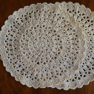 May include: Two white crocheted doilies with a delicate floral pattern.