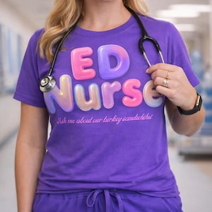 Può includere: Una maglietta viola con le parole "ED Nurse" in lettere a bolla. Sotto il testo c'è la frase "Ask me about our turkey sandwiches" in corsivo. Uno stetoscopio è intorno al collo.