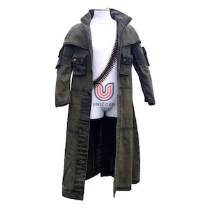 Può includere: Un lungo cappotto verde oliva con più tasche e un ampio colletto. Una bandoliera di proiettili è drappeggiata sul petto. Il cappotto è esposto su un manichino. Il cappotto ha un aspetto usurato.
