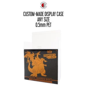 May include: A white custom-made display case with the text "CUSTOM-MADE DISPLAY CASE ANY SIZE 0.5mm PET". The case is open, revealing a black box with orange graphics and the text "CHAMPION'S PATH ELITE TRAINER BOX".