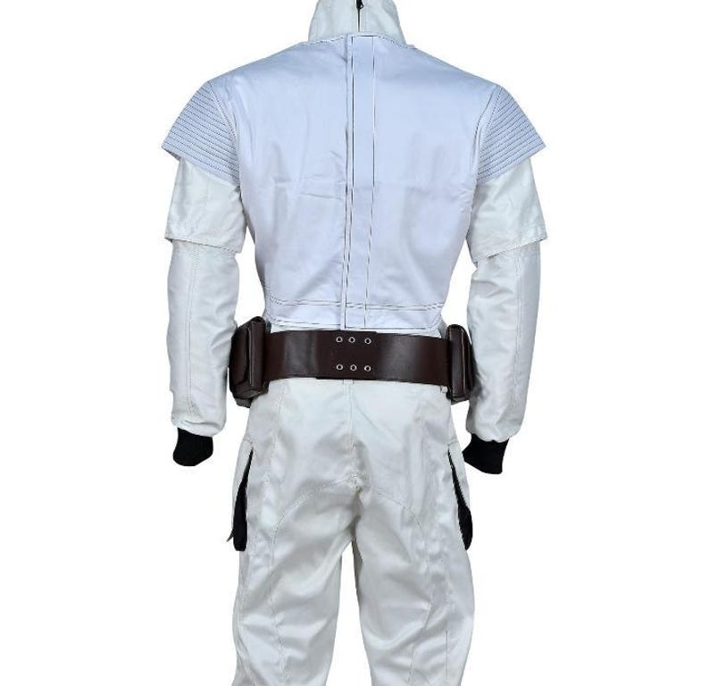 May include: A white jumpsuit with a high collar and a brown belt with pouches. The suit has a quilted design on the shoulders and a zipper down the front. Black cuffs are visible at the wrists and ankles. The overall design suggests a futuristic or military theme.