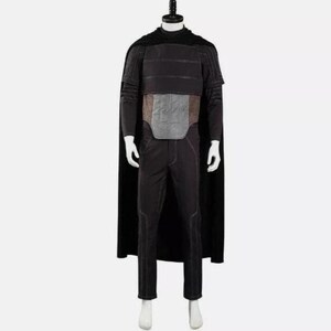 Pode incluir: Um conjunto de fantasia preto composto por uma capa longa, uma blusa de manga comprida com costuras horizontais e um painel central cinzento retangular no peito. O traje inclui cal&ccedil;as pretas a combinar com detalhes de costura subtis.