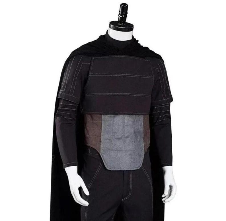 Pode incluir: Um conjunto de traje preto composto por uma capa longa, uma camisa de manga comprida com costuras verticais subtis e uma pe&ccedil;a de peito em camadas. O tronco inclui um painel abdominal retangular cinzento-escuro acolchoado sobre cal&ccedil;as pretas.