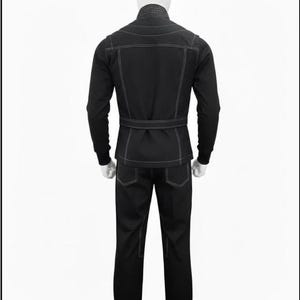 May include: A black jacket and matching trousers set featuring prominent white contrast stitching. The jacket includes a high collar, long sleeves with ribbed cuffs, and a belted waist. The trousers feature back pockets and a straight-leg design.