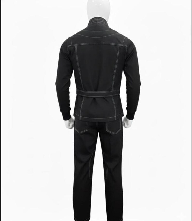 May include: A black jacket and matching trousers set featuring prominent white contrast stitching. The jacket includes a high collar, long sleeves with ribbed cuffs, and a belted waist. The trousers feature back pockets and a straight-leg design.