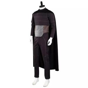 Pode incluir: Um conjunto de fantasia preto composto por uma capa longa, uma pe&ccedil;a peitoral estruturada com costuras horizontais, um painel central cinzento e cal&ccedil;as pretas a combinar. O conjunto inclui mangas compridas com padr&otilde;es de linhas detalhados.