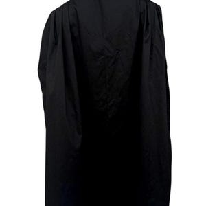 May include: A long, floor-length black cape featuring a high collar and a structured, pleated design. The garment is draped over a mannequin, showing a solid black fabric with a smooth texture and a clean, minimalist silhouette from the back view.