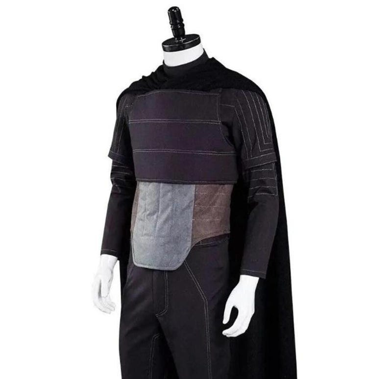 Pode incluir: Um conjunto de fantasia preto composto por uma capa longa, uma camisa de manga comprida com gola alta e detalhes de costura branca, uma placa peitoral preta com costuras horizontais, um protetor abdominal cinza e cal&ccedil;as pretas num manequim.
