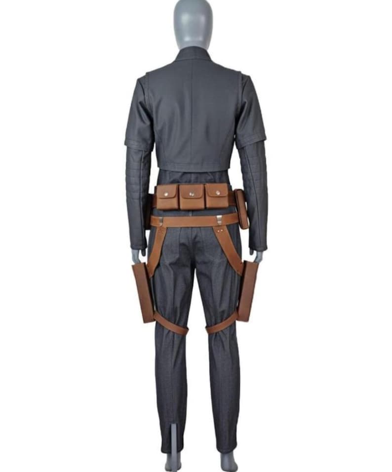 May include: A dark gray long-sleeved jacket and matching trousers worn on a mannequin. The outfit includes a brown leather utility belt with three small pouches and two holster-like attachments hanging down the sides of the legs.