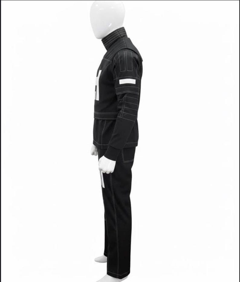 May include: A black long-sleeved jacket and matching trousers set featuring a high collar, white geometric accents on the chest and sleeves, and prominent white topstitching throughout the garment, displayed on a white mannequin torso.