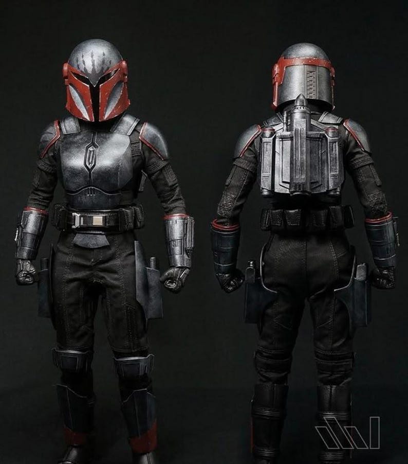 May include: A collectible action figure of a warrior in black and red armour, shown from front and back views. The figure wears a metallic helmet with a T-shaped visor, a chest plate, gauntlets, a utility belt, and a jetpack on the back.
