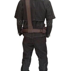 Puede incluir: Un conjunto de estilo t&aacute;ctico negro que consta de una chaqueta de manga corta y pantalones a juego con costuras blancas en contraste. La chaqueta presenta patrones geom&eacute;tricos en las mangas y un cintur&oacute;n utilitario marr&oacute;n con bandolera.