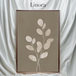 May include: A framed botanical print with a beige eucalyptus branch design on a taupe background. The artwork is enclosed in a brown frame and set against white fabric. The word "Linora" is at the top.