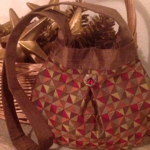 Cartera de noche con diseño geométrico en rojo, marrón y dorado
