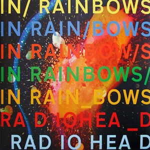 May include: Album artwork for Radiohead's "In Rainbows." The design features the words "IN RAINBOWS" in various colours and orientations, layered over a colourful, abstract background with a black backdrop. The band's name, "RADIOHEAD," is also displayed.