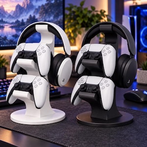 Può includere: Due supporti verticali per accessori da gioco, uno bianco e uno nero, ciascuno dotato di un gancio superiore per cuffie e due alloggiamenti inferiori che ospitano controller di gioco wireless bianchi. I supporti hanno una base circolare.