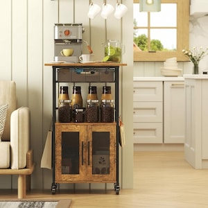 May include: A rustic kitchen cart with a black metal frame and a wooden cabinet. It features a coffee maker, jars of coffee beans, and a drawer. The cart is on wheels and has a cabinet with glass doors.