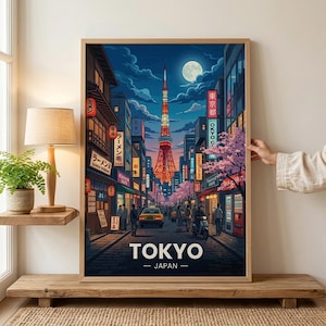 May include: A framed art print depicting a nighttime street scene in Tokyo, Japan. The image features the Tokyo Tower, illuminated signs, cherry blossoms, and the text "TOKYO - JAPAN". The artwork is in a wooden frame.