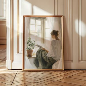 Può includere: Una stampa artistica incorniciata raffigura una persona che legge vicino a una finestra. L'opera d'arte presenta una donna con una camicia bianca e una gonna verde, seduta vicino a una finestra con tende trasparenti. Una pianta in vaso è sul davanzale e la cornice ha una finitura dorata.