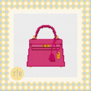 May include: A cross-stitch pattern featuring a vibrant fuchsia handbag with a single top handle, a central horizontal strap, and gold-colored hardware accents including a small hanging charm. The design is set against a light gray grid background.