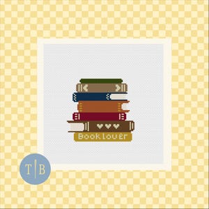 May include: A cross-stitch pattern featuring a stack of six books in various colors including green, tan, blue, orange, red, and brown. The bottom book is yellow and displays the text Book lover in white, while the brown book features three white hearts.