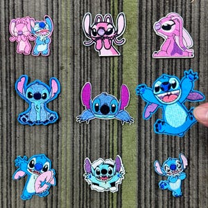 May include: A selection of embroidered patches featuring the character Stitch from Lilo & Stitch. The patches depict Stitch in various poses and colours, including blue and pink, with detailed stitching.