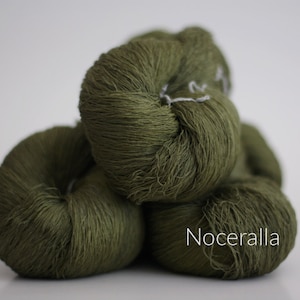 May include: Three skeins of green yarn, stacked on top of each other. The yarn is a soft, fuzzy texture. The label on the bottom skein reads "Noceralla".