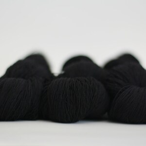May include: Four balls of black yarn, arranged in a row.