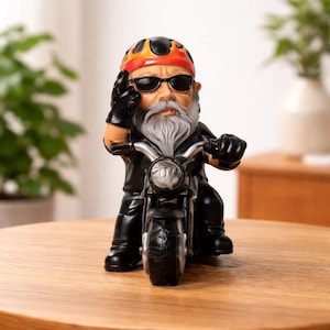 Op de afbeelding: Een beeldje van een biker-kabouter op een zwarte motor. De kabouter draagt een rood-zwarte helm, een zonnebril en een zwarte leren jas. De kabouter heeft een lange grijze baard en maakt een handgebaar.