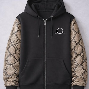 May include: Black zip-up hoodie with a hood and a white circular logo on the chest. The sleeves feature a snakeskin pattern in shades of brown and tan. The hoodie has a full-length zipper and black cuffs.