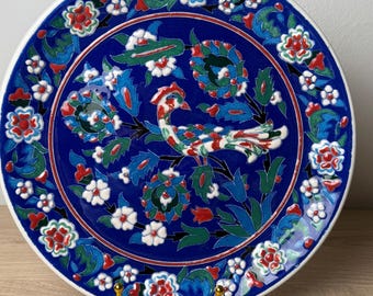 Plato Kütahya de pavo real hecho a mano: Cerámica artística de estilo Iznik con motivos florales azules (25 cm de diámetro)