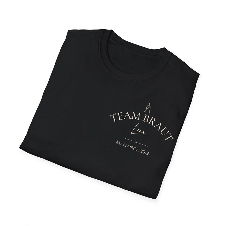 May include: A black t-shirt featuring white text that reads TEAM BRAUT with a small graphic of two clinking champagne glasses above it. Below the text is the name Lena in script, followed by a small heart and the text MALLORCA 2026.