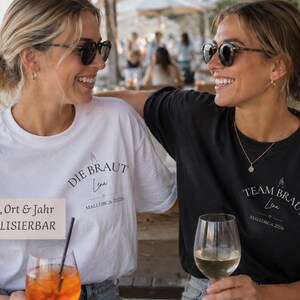 May include: A white t-shirt with the text DIE BRAUT, Lena, and MALLORCA 2026, and a black t-shirt with the text TEAM BRAUT, Lena, and MALLORCA 2026. Both shirts feature a small graphic of a hand holding a glass above the printed text.