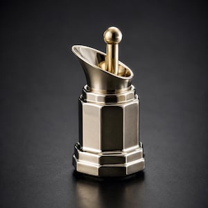 May include: A polished gold-tone metal sugar pourer featuring a hexagonal base and a slanted spout. The vessel includes a central vertical rod topped with a small sphere, designed for dispensing granulated sugar through the angled opening.