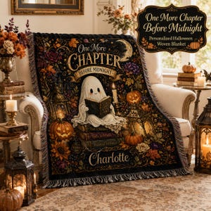 Peut inclure: Une couverture tissée représentant un fantôme lisant un livre sur une pile d'ouvrages, entouré de citrouilles, de lanternes et de feuilles d'automne. Le texte indique One More Chapter Before Midnight et Charlotte, avec un croissant de lune.