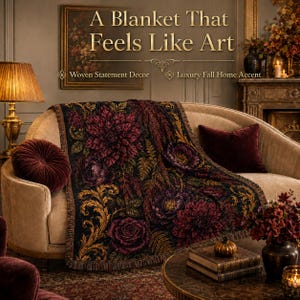 May include: A woven blanket featuring a dark floral pattern with deep burgundy and purple flowers, green foliage, and gold scrollwork accents. The text A Blanket That Feels Like Art, Woven Statement Decor, and Luxury Fall Home Accent is visible.