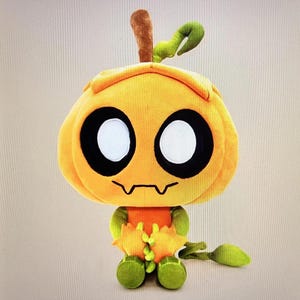 Pode incluir: Um brinquedo de pel&uacute;cia em forma de personagem semelhante a uma ab&oacute;bora. O brinquedo &eacute; principalmente laranja com olhos grandes pretos e brancos, uma boca irregular e detalhes verdes e marrons. Possui um caule e detalhe de folha no topo e p&eacute;s verdes.